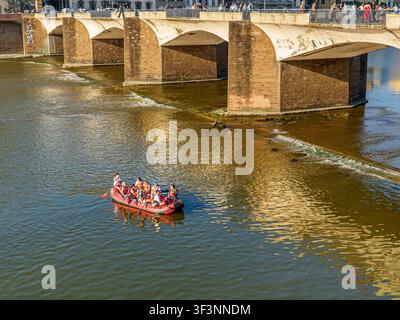 Florenz, Toskana, Italien. 28. Mai 2026. - Eine Gruppe von Touristen in einem roten Aufblasenboot fährt an einem sonnigen Tag unter einer historischen Steinbrücke in der Stad Stockfoto