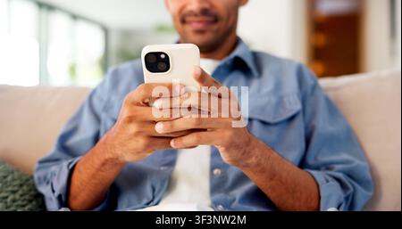 Telefon, Hände und Mann auf dem Sofa zu Hause zum Schreiben von Nachrichten, E-Mails oder Social Media auf der mobilen App im Wohnzimmer. Technologie, Tippen und Person am Handy für Stockfoto
