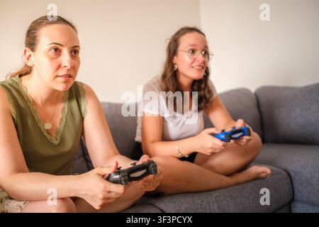 Junge Frauen sitzen auf einem Sofa und spielen mit Videospiel-Controllern Stockfoto