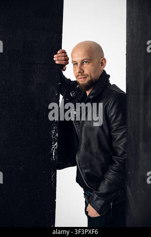 Mann steht in einem StudioSetting in der Nähe dunkler Paneele während einer Fotoshoot-Session Stockfoto