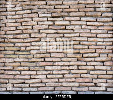 Textur einer alten Ziegelwand aus hellbraunen und beigen Ziegeln. Die raue Oberfläche mit natürlichen Unvollkommenheiten eignet sich perfekt als Hintergrund für Archi Stockfoto