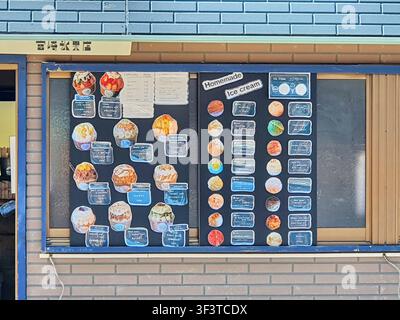 Eine detaillierte Ansicht einer Außentafel mit Speisekarte in einem japanischen Dessertladen namens "宫崎氷果店" (Miyazaki Hyokaten). Die Anzeige ist an einer Ziegelwand unterhalb montiert Stockfoto