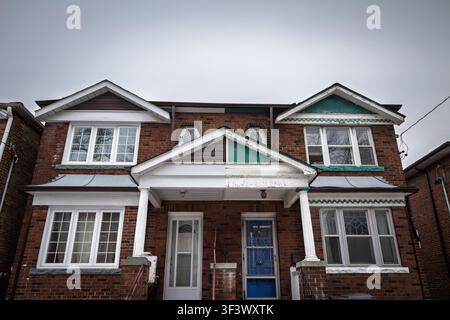 Edwardianisches Backstein-Doppelhaus in Toronto, Ontario, Kanada, mit zwei Eingängen, Säulen an der vorderen Veranda, weißen Fenstern und Details der Wohnhausfassade verknüpft Stockfoto