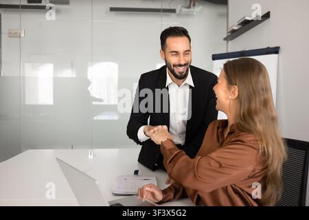 Zufriedene multikulturelle Kollegen, die sich am Arbeitsplatz mit dem Fauststoß begrüßen Stockfoto