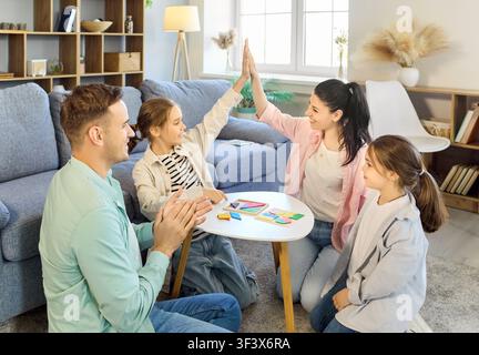 Glückliche Familie mit Eltern und Kindern, die zusammen zu Hause ein Brettspiel spielen Stockfoto