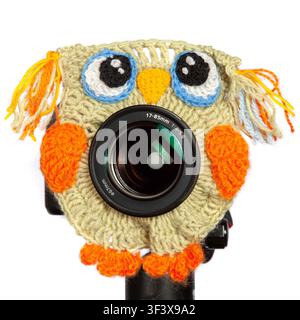 Kameraobjektiv mit einem handgestrickten Eulen-Cozy bedeckt. Stockfoto