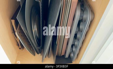 Vertikaler Stapel von Backblechen und Pfannen im Schrank Stockfoto