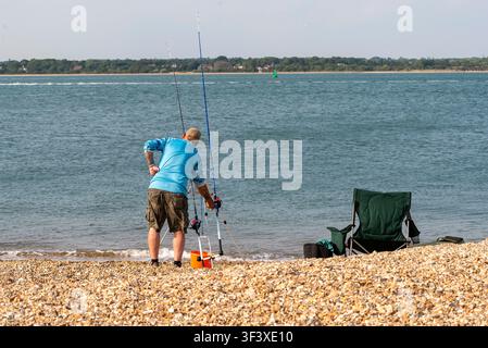 Southampton Water England UK. 23.07.2026. Ein einsamer Angler bereitet seine Ausrüstung an einem sonnigen Tag vor, wobei er zwei Ruten in das Southampton Water UK auswirft. Stockfoto