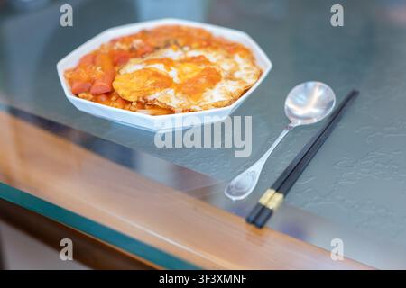 Koreanisch-stilisiertes Kimchi-Fleischreis mit Ei und Wurst, serviert in einer weißen achteckigen Schüssel, begleitet von Stockfoto
