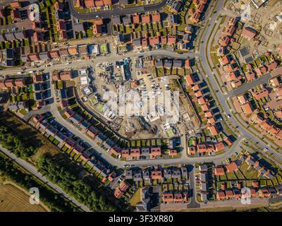 Luftaufnahme von oben über einer großen Baustelle, auf der neue und erschwingliche umweltfreundliche Häuser mit Solarpaneelen im Vereinigten Königreich auf Grünland gebaut werden. N Stockfoto