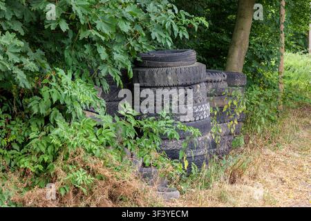 Alte gebrauchte Autoreifen unter grünen Bäumen in Coesfeld, Deutschland entsorgt Stockfoto