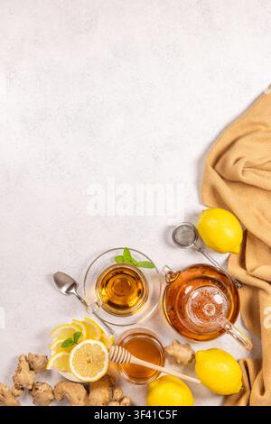 Warmer Kräutertee in einer Glas Tasse und Teekanne, serviert mit frischen Zitronenscheiben, Ingwerwurzeln, Honig und Minze, symbolisiert Wellness, Entspannung und Immuni Stockfoto