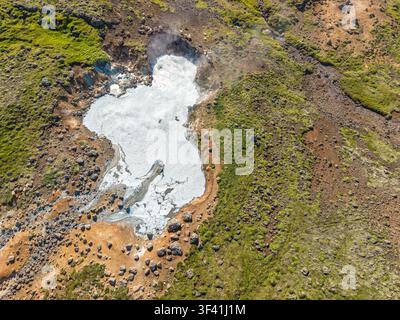 Luftaufnahme von geothermalen Schlammbecken, Mineralablagerungen, vulkanischem Gestein und grüner Vegetation, die natürliche Muster in Island bilden. Stockfoto