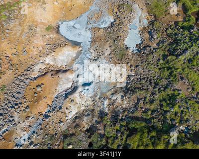 Luftaufnahme von geothermalen Schlammbecken, Mineralablagerungen, vulkanischem Gestein und grüner Vegetation, die natürliche Muster in Island bilden. Stockfoto
