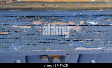 Verwitterte blaue Farbe blättert über eine Holzoberfläche. Risse und Abnutzung erzählen die Geschichte von Zeit und Nutzung. Rost und verblasste Farbe verleihen dem Holz Charakter. Ideal fo Stockfoto