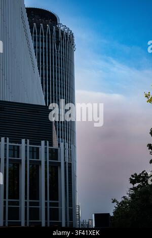Eine dramatische Niedrigwinkelaufnahme fängt einen Wolkenkratzer in Madrid ein, dessen außergewöhnliche gezackte und unregelmäßige Krone sich vor einem blassrosa und blauen Abendhimmel abhebt Stockfoto