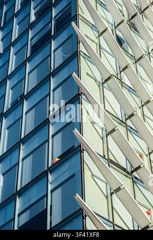 Ein auffälliger architektonischer Detailbild fängt die Verbindungsstelle zweier kontrastierender Glasfassaden ein – tiefblaue Paneele links treffen auf hellgrünes Glas fi Stockfoto
