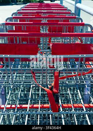 Nahaufnahme von leeren Einkaufswagen mit roten Griffen auf dem Supermarktparkplatz Stockfoto