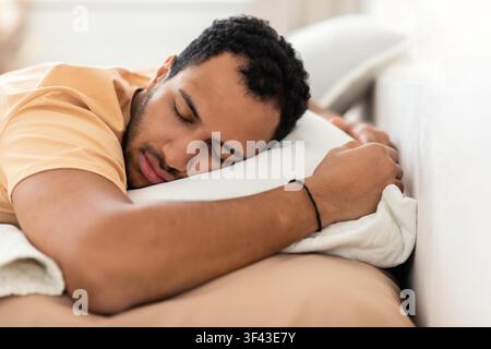 Schlafender junger schwarzer Mann, der zu Hause auf einem Kissen ruht, Entspannung und Selbstfürsorge-Konzept Stockfoto