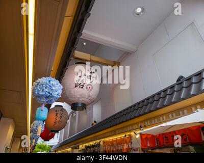 Kamakura, Japan – 21. Juni 2026: Traditionelle Papierlaternen und Blumendekorationen, die am Eingang der Einkaufsstraße Komachi-dori hängen. Stockfoto