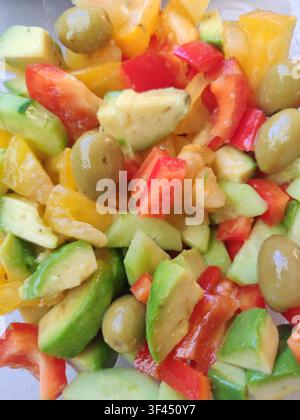 Nahaufnahme von frischem grünen Salat mit Gurke, Tomate, Avocado, Oliven und Olivenöl, Konzept für gesunde, saubere Ernährung Stockfoto