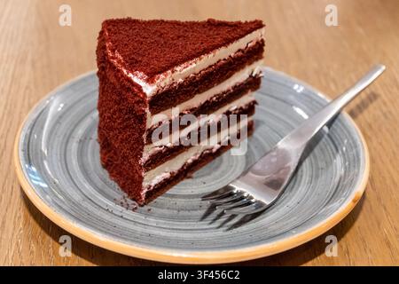 Red Velvet Cake Schichten der Dekadenz auf einem strukturierten Teller Stockfoto