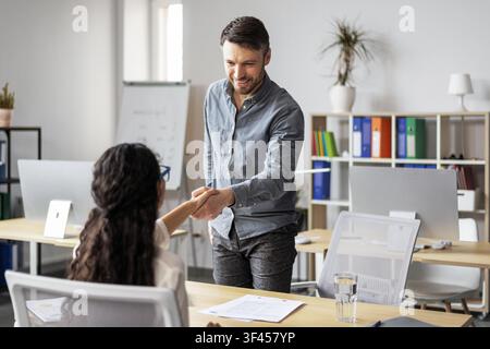 Mann, der einer Frau im Büro die Hand schüttelt, Geschäftsbesprechungskonzept Stockfoto