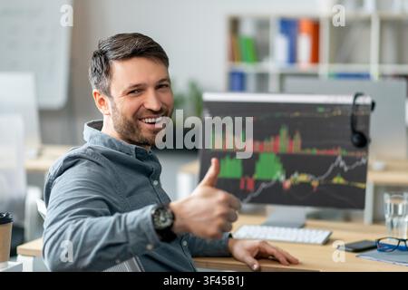 Glücklicher kaukasischer männlicher Aktienhändler feiert Erfolg im Büro, Geschäftskonzept Stockfoto
