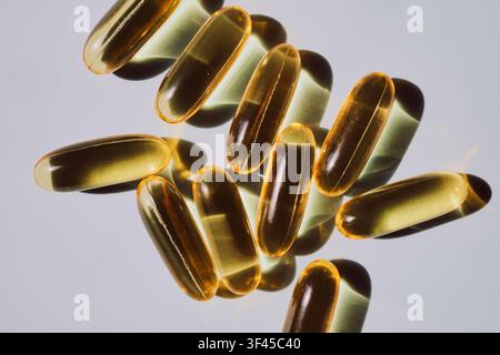 Goldene Softgel-Kapseln, die Nahrungsergänzungsmittel für einen gesunden Lebensstil hervorheben Stockfoto