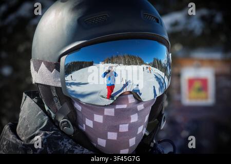 Ein Skifahrer mit Helm und verspiegelter Skibrille auf einer Skipiste. *** Ein Skifahrer trägt einen Helm und verspiegelte Skibrillen auf einer Skipiste Stockfoto