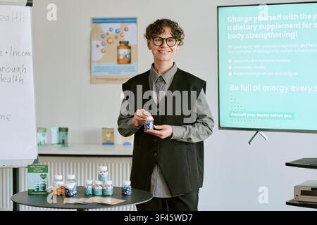 Porträt einer jungen Erwachsenen, die Nahrungsergänzungsmittel im Training präsentiert Stockfoto