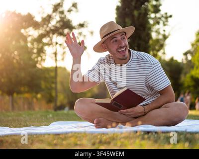 Junger Mann genießt das Lesen eines Buches in einem Park an einem Sommertag. Stockfoto