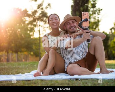 Ein fröhliches Paar teilt einen verspielten Moment, während es sich in einem malerischen Park aufnimmt. Stockfoto