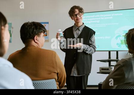 Junge erwachsene Frau präsentiert ein Nahrungsergänzungsmittel während einer Geschäftsschulung Stockfoto
