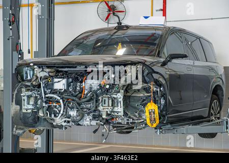 Elektrofahrzeug, das in einer modernen Autowerkstatt gewartet wird. Professionelle Fahrzeugdiagnose, Reparatur, elektrische Mobilität Stockfoto