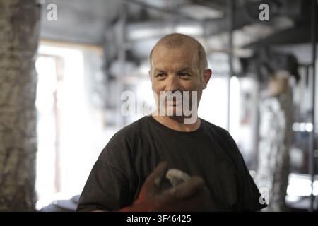Erfahrener Handwerker lächelt in seiner Werkstatt Stockfoto