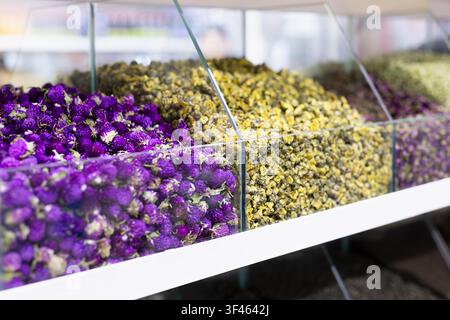 Getrocknete Blumen und Kräutertee in Gläsern auf einem orientalischen Basar in Bukhara. Bunte violette und gelbe Blüten schaffen eine lebhafte Marktszene Stockfoto