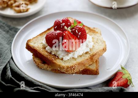 Ein Toast mit Erdbeeren, Käse und Nüssen auf einem Teller auf dem Tisch Stockfoto