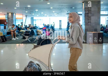 Junge Reisende mit Trolley im überfüllten Wartebereich des Flughafens, Reise- und Abreisekonzept. Stockfoto