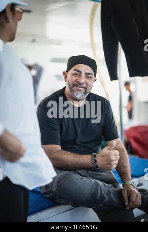Freundlicher bärtiger Mann lächelt und zeigt einen Daumen hoch Stockfoto