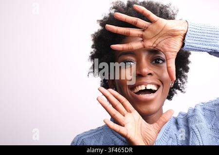 Fröhliche schwarze Frau, die mit ihren Händen einen Rahmen bildet Stockfoto