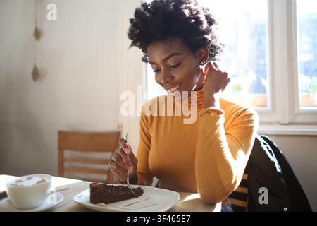 Junge schwarze Frau genießt Kaffee und eine Kuchenstückchen Stockfoto