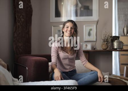 Fröhliche Frau lächelt in die Kamera im Wohnzimmer Stockfoto
