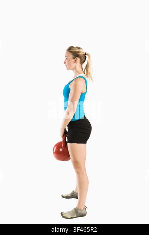 Fitte Frau steht mit Kettlebell da, bevor sie Good Morning ausführt Stockfoto