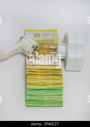 Elektrische Steckdose und Steckstecker, die auf Euro-Banknoten platziert sind, veranschaulichen steigende Strompreise, zunehmende Energiekosten, Stromrechnungen, i Stockfoto