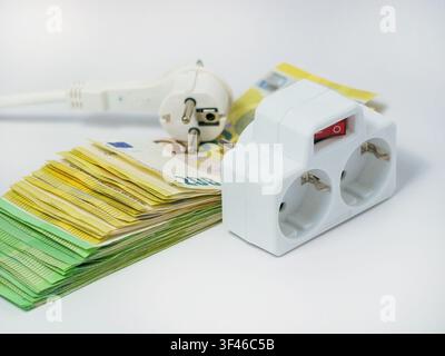 Elektrische Steckdose und Steckstecker, die auf Euro-Banknoten platziert sind, veranschaulichen steigende Strompreise, zunehmende Energiekosten, Stromrechnungen, i Stockfoto