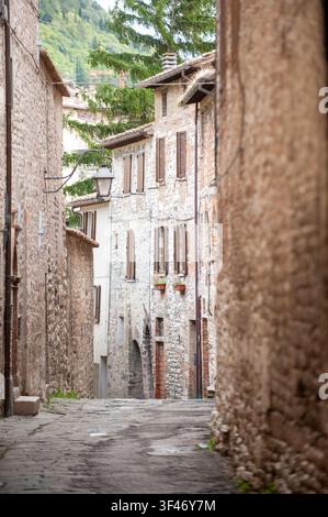 Schmale Kopfsteinpflastergasse zwischen mittelalterlichen Steinhäusern im historischen Zentrum von Gubbio, Umbrien, Italien Stockfoto