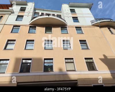 Ein beiges Wohnhaus mit modernen geometrischen Formen, großen Fenstern und geschwungenen Balkonstrukturen. Das Bild zeigt urbane Architektur Stockfoto