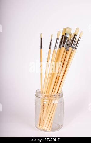 Gläsernes Glas mit Pinseln im Künstlerarbeitsplatz Stockfoto