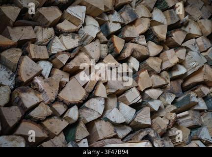 Stapel gehackten Brennholzes mit Baumstumpf im Vordergrund. Vorbereitetes Brennholz für die Winterheizung. Stockfoto